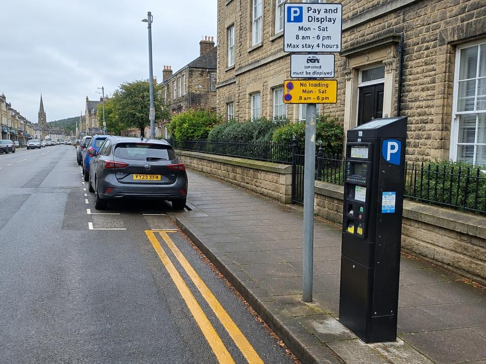UK street with double yellow lines, parking signs and a pay and display machine